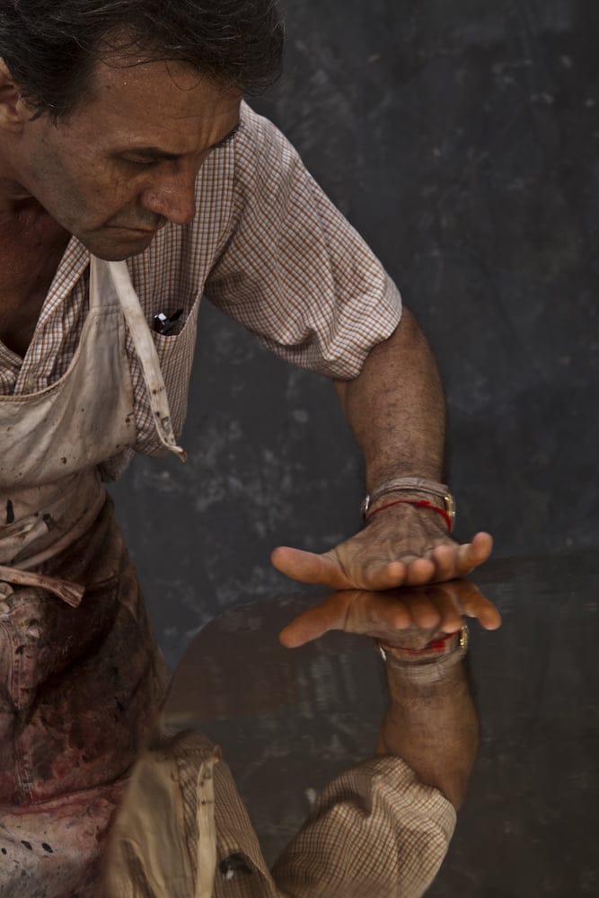 Eric Stocker — the master's hand touching a lacquered surface, reflected in perfect black lacquer